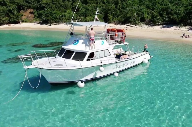 A snorkel boat anchored in turquoise water off a sandy beach