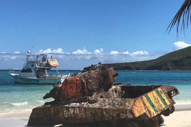 The rusting, graffiti-painted tank at the water's edge on Flamenco Beach, Culebra, a boat anchored beyond