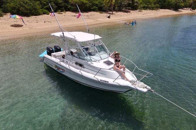 A small sport-fishing boat anchored off a sandy beach, seen from above