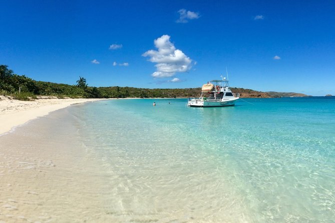 A snorkel boat anchored off a white-sand beach under a blue sky